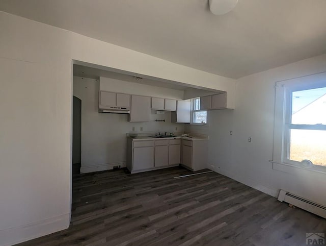 kitchen with a baseboard heating unit, light countertops, dark wood-style floors, and baseboards