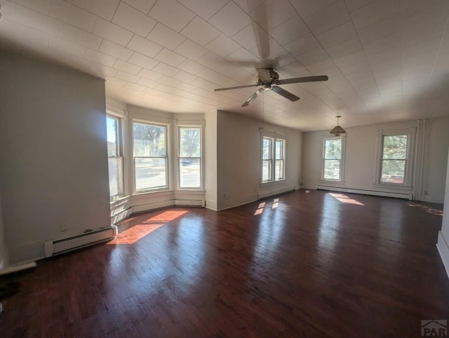 empty room with baseboard heating, a baseboard radiator, dark wood finished floors, and a healthy amount of sunlight