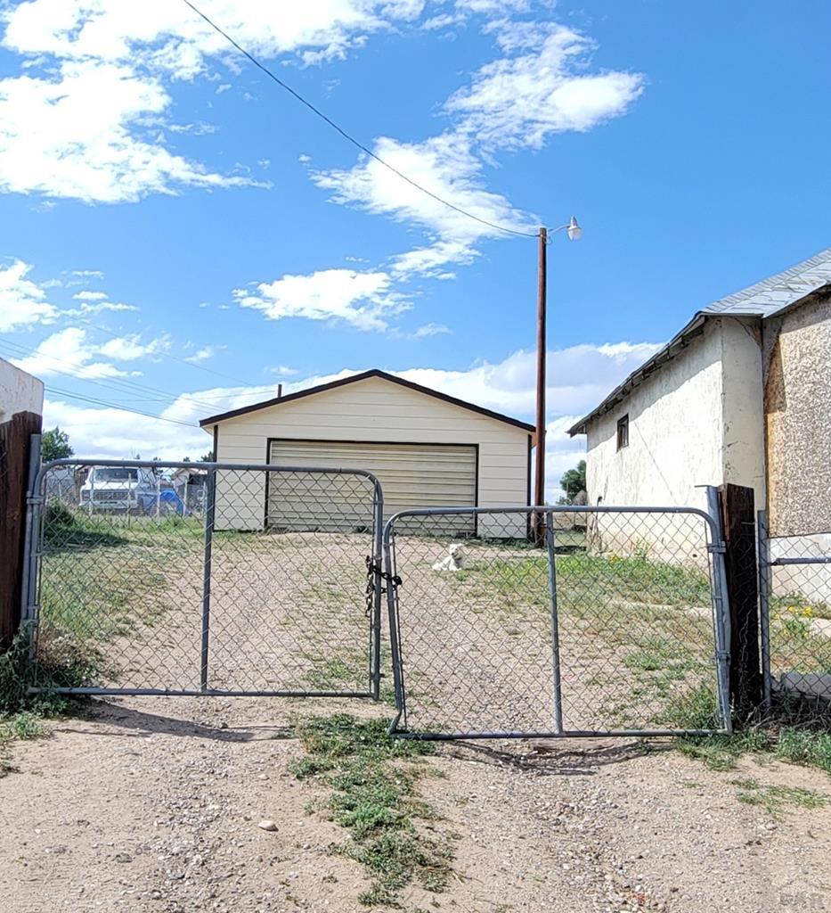 620 W 4th St, Walsenburg, CO 81089 - view of yard featuring a garage, an outdoor structure, and a gate