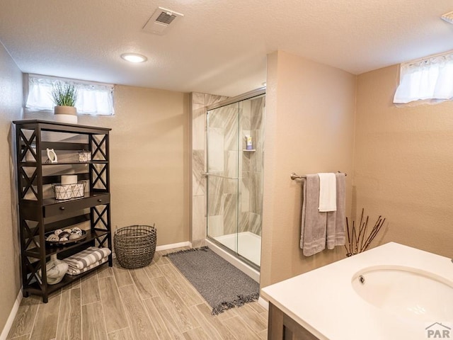 full bathroom featuring a stall shower, visible vents, vanity, and wood tiled floor