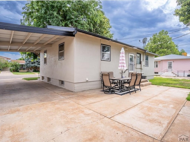 rear view of house featuring a patio, outdoor dining area, driveway, and stucco siding