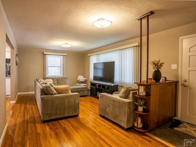 living area featuring a textured ceiling, wood finished floors, and baseboards