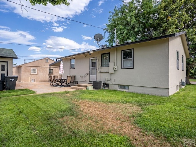 back of house with central air condition unit, stucco siding, a lawn, and a patio