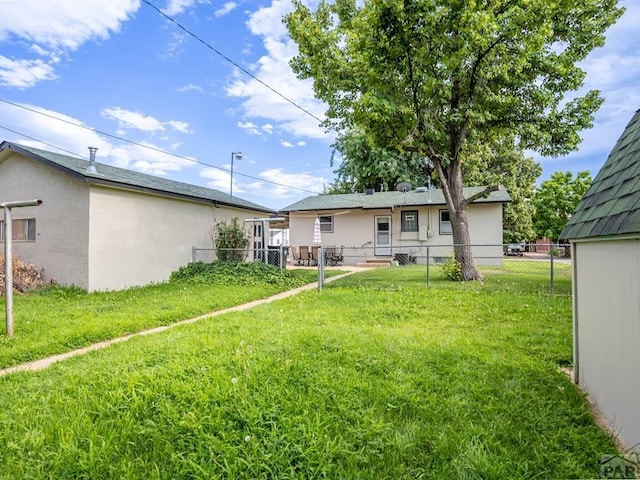 rear view of property with a yard, fence, and stucco siding