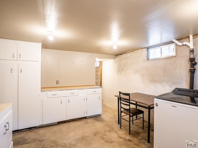 kitchen featuring washer / dryer, white cabinets, light countertops, and concrete floors