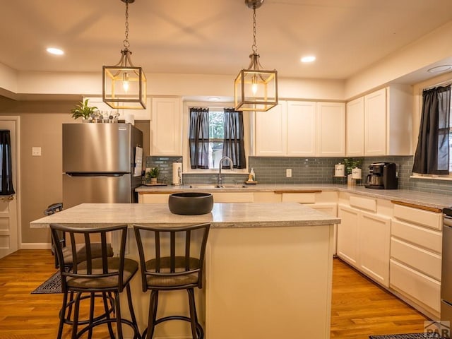 kitchen with freestanding refrigerator, white cabinetry, and a center island