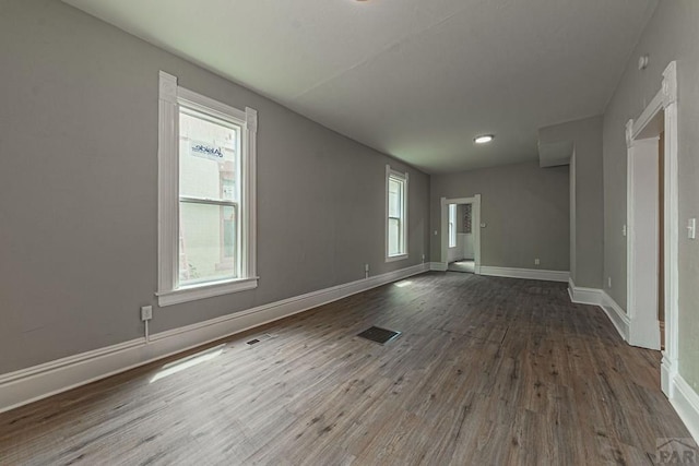 unfurnished room with visible vents, baseboards, and dark wood-style flooring