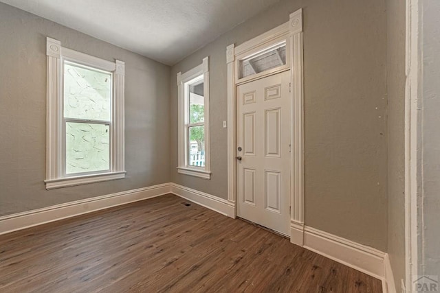 foyer entrance with dark wood-style floors and baseboards