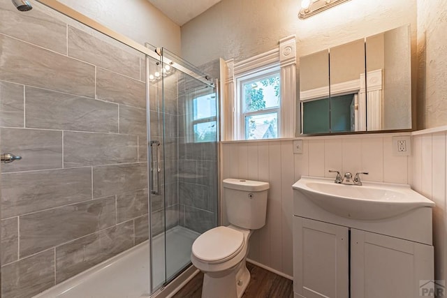 bathroom featuring vanity, a shower stall, toilet, and wood finished floors