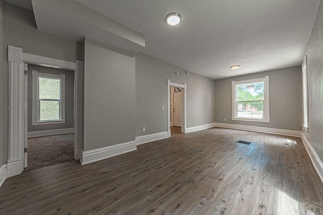 spare room with visible vents, baseboards, and dark wood-type flooring