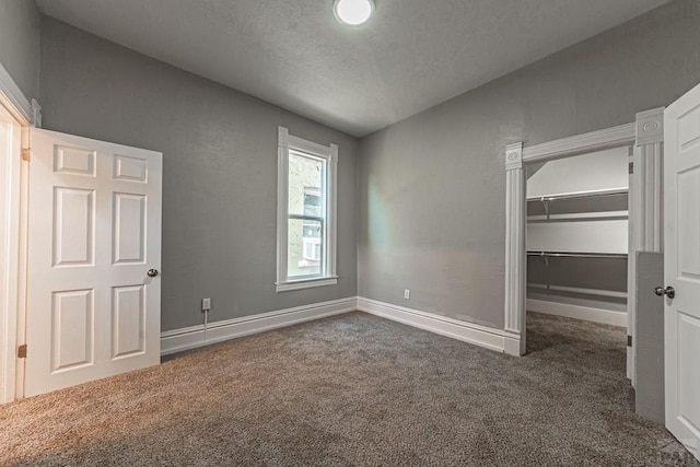 unfurnished bedroom featuring a walk in closet, baseboards, and carpet floors