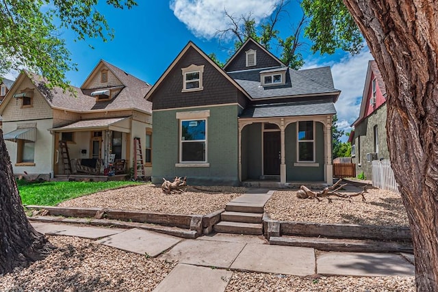 view of front of home featuring a porch, fence, brick siding, and a shingled roof