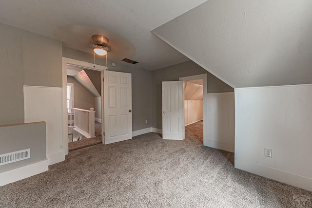 additional living space with carpet flooring, baseboards, visible vents, and vaulted ceiling