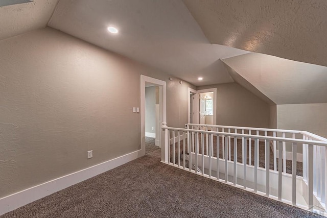 additional living space with lofted ceiling, carpet flooring, a textured wall, and baseboards