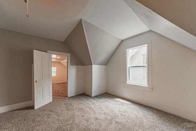 bonus room with vaulted ceiling, carpet floors, and a textured ceiling