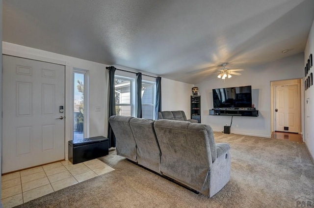 living area with lofted ceiling, light tile patterned floors, ceiling fan, and light colored carpet