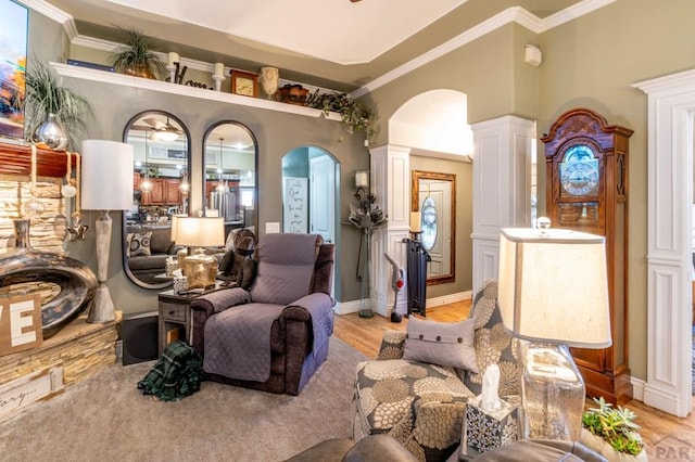 sitting room featuring ornate columns, arched walkways, light wood finished floors, and ornamental molding