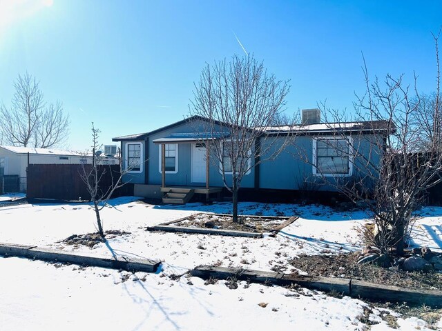 snow covered rear of property with fence