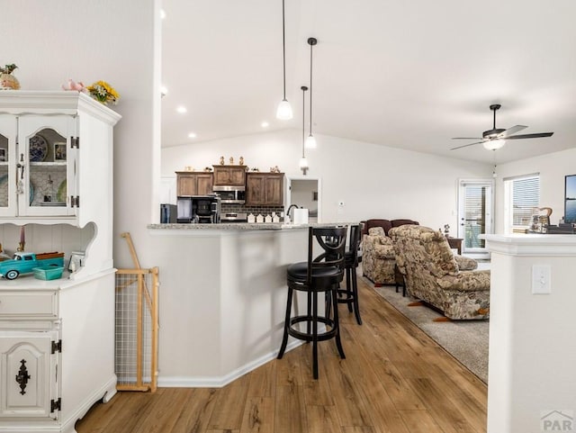 1700 Kingfisher Ln, Pueblo, CO 81008 - kitchen with a kitchen bar, light wood-type flooring, ceiling fan, stainless steel microwave, and lofted ceiling