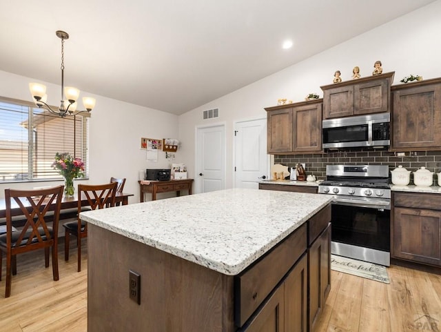 1700 Kingfisher Ln, Pueblo, CO 81008 - kitchen featuring appliances with stainless steel finishes, vaulted ceiling, a kitchen island, tasteful backsplash, and light wood-style flooring