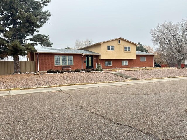 tri-level home featuring fence and brick siding