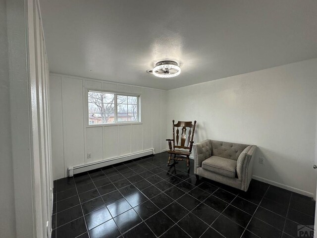 living area with dark tile patterned floors, a baseboard radiator, and baseboards