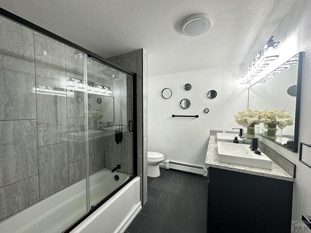 bathroom with double vanity, bath / shower combo with glass door, toilet, baseboard heating, and a sink