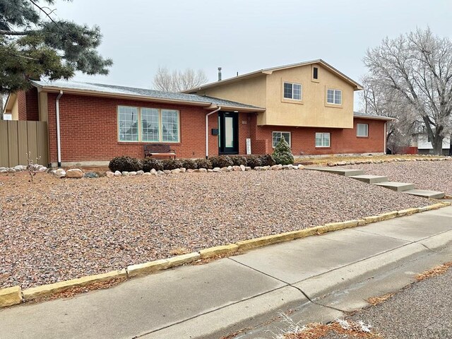 tri-level home with brick siding and fence