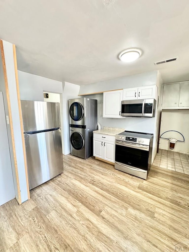 209 Beymer, Cheraw, CO 81030 - kitchen with appliances with stainless steel finishes, estacked washer and dryer, light wood-style floors, white cabinetry, and light countertops