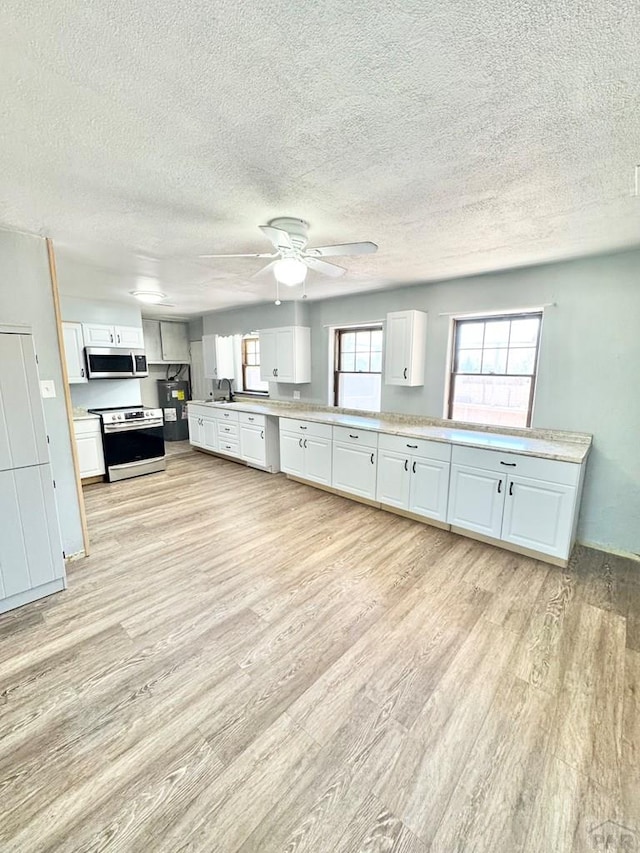 209 Beymer, Cheraw, CO 81030 - kitchen with appliances with stainless steel finishes, light wood-style flooring, white cabinets, light countertops, and a textured ceiling