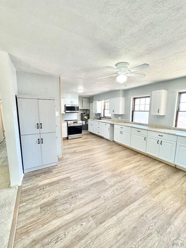 209 Beymer, Cheraw, CO 81030 - kitchen with stainless steel appliances, light wood-style floors, white cabinetry, a textured ceiling, and a ceiling fan