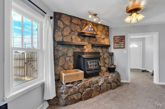 living room featuring carpet floors, a wood stove, and baseboards