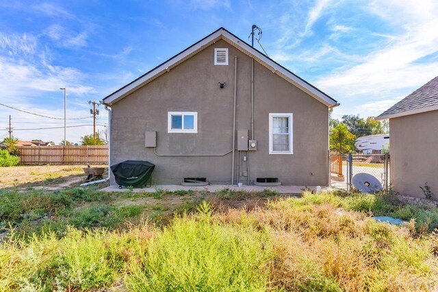 rear view of house with fence and stucco siding