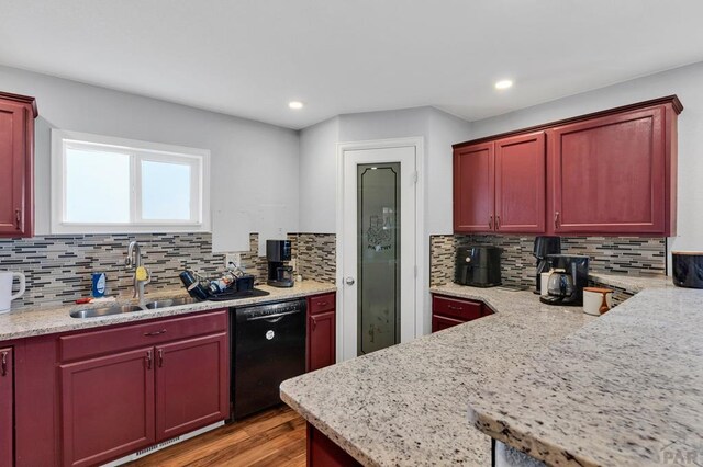 kitchen with a sink, dark brown cabinets, light wood-type flooring, light stone countertops, and dishwasher