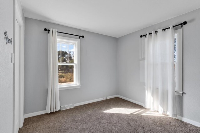 carpeted spare room featuring baseboards and visible vents