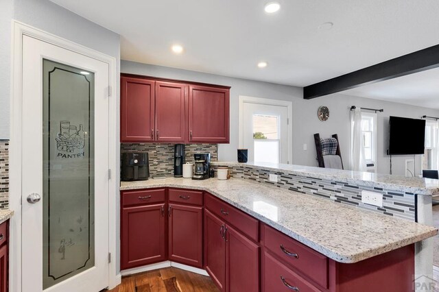 kitchen with dark wood finished floors, recessed lighting, decorative backsplash, open floor plan, and a peninsula