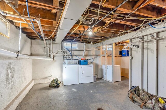 basement featuring washing machine and dryer, visible vents, and fridge