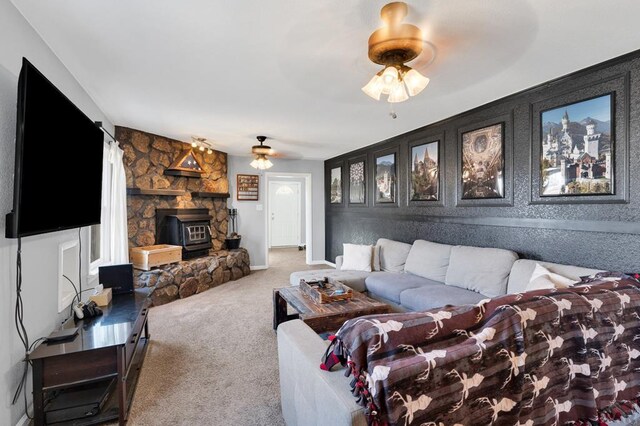 carpeted living room featuring ceiling fan, a wood stove, and baseboards