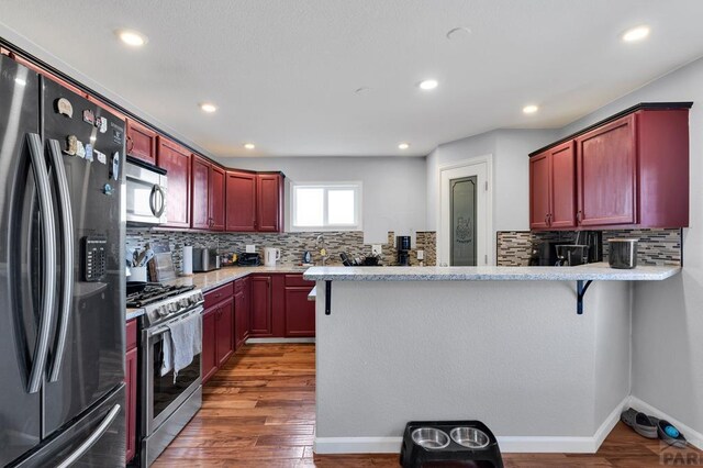 kitchen featuring a peninsula, dark wood-style floors, appliances with stainless steel finishes, and dark brown cabinets