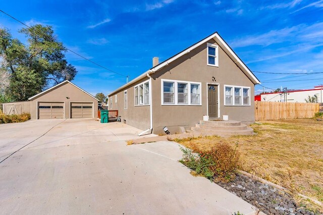 bungalow-style house with a garage, fence, an outdoor structure, and stucco siding