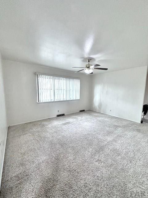 empty room with ceiling fan, visible vents, and carpet flooring