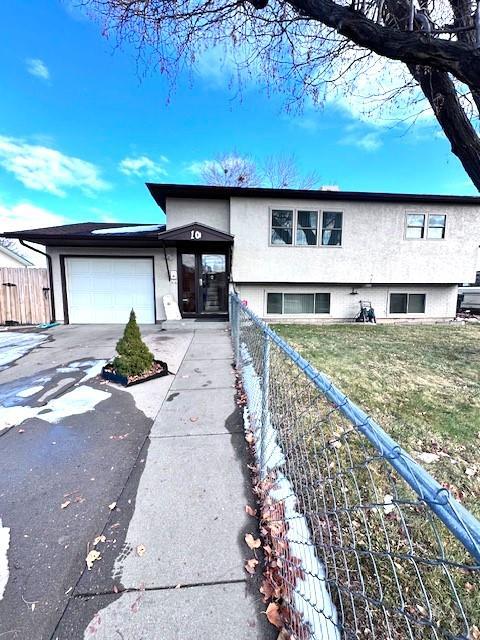 view of front of home featuring a garage, fence, concrete driveway, and a front yard