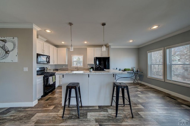 kitchen with black appliances, a sink, white cabinets, and a center island