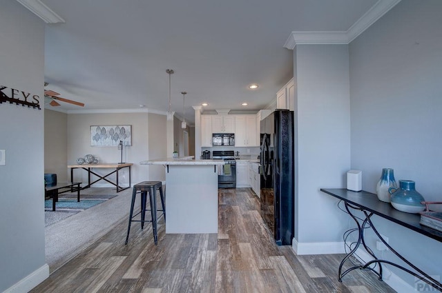 kitchen with a breakfast bar, pendant lighting, light countertops, white cabinetry, and black appliances