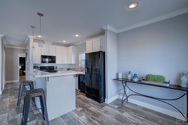 kitchen with a breakfast bar area, white cabinets, hanging light fixtures, black appliances, and crown molding