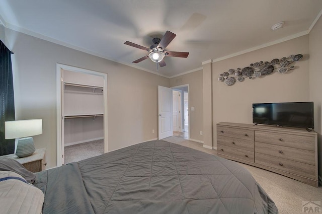 bedroom featuring light carpet, ornamental molding, a walk in closet, and baseboards