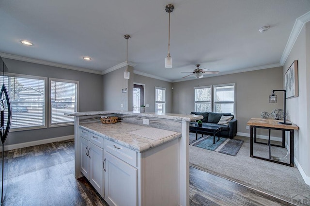 kitchen featuring baseboards, white cabinets, a kitchen island, open floor plan, and pendant lighting