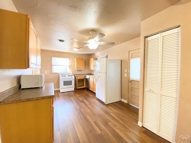 1624 Garwood Dr, Pueblo, CO 81005 - kitchen with white appliances, a ceiling fan, dark wood finished floors, dark countertops, and light brown cabinetry