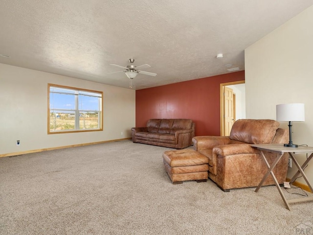 living room with a textured ceiling, baseboards, a ceiling fan, and light colored carpet