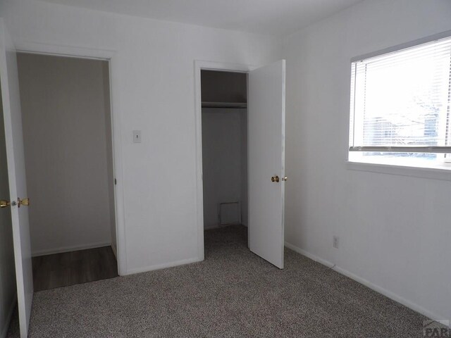 unfurnished bedroom featuring a closet, carpet flooring, and baseboards